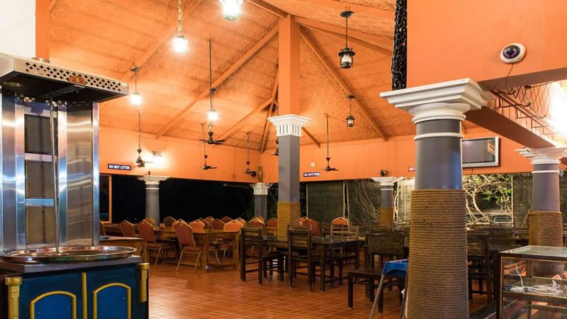 Spacious open-air dining area with tables, chairs and high covered ceiling