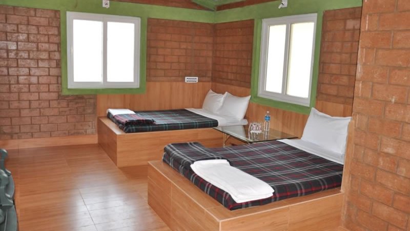 Twin bedroom with wooden beds, brick walls and large windows
