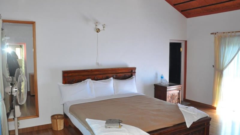 Spacious bedroom with wooden double bed, side table and large windows