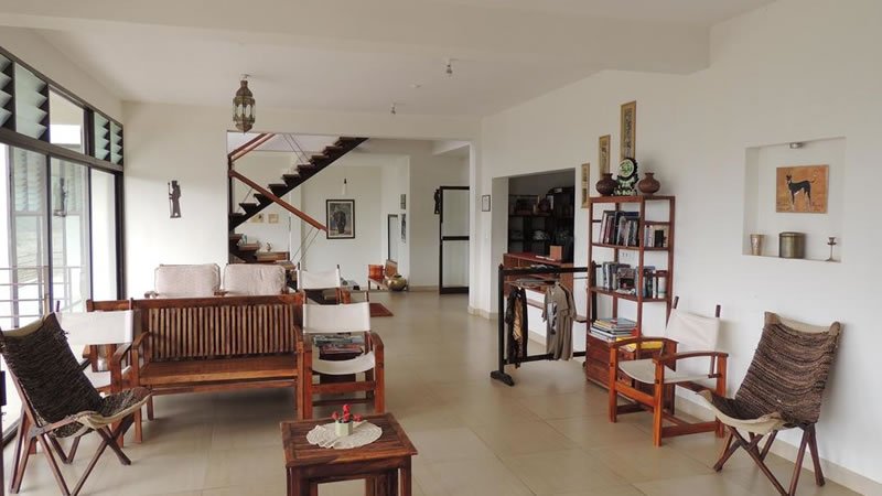 Spacious living room with wooden seating, bookshelf, large windows and open interior