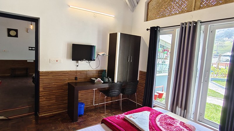 Bedroom with work desk, wardrobe and balcony access through large glass doors with natural light