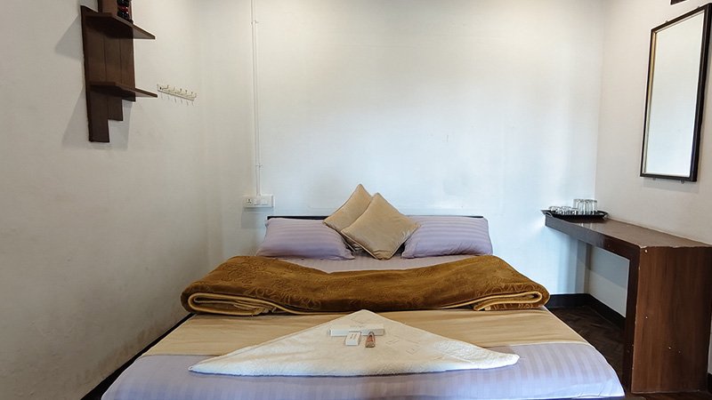 Standard bedroom with comfortable bed, wall mirror and minimal wooden furniture setup