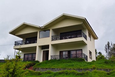 Cottage with multiple balconies surrounded by green grass and plants