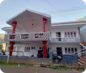 Two-storey cottage with red pillars, decorative balcony railing and covered entrance