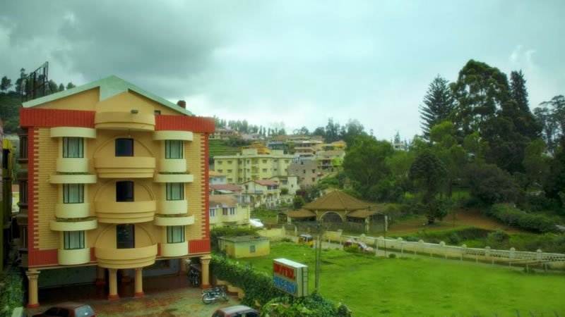 Multi-storey building overlooking a green lawn, trees and surrounding hillside