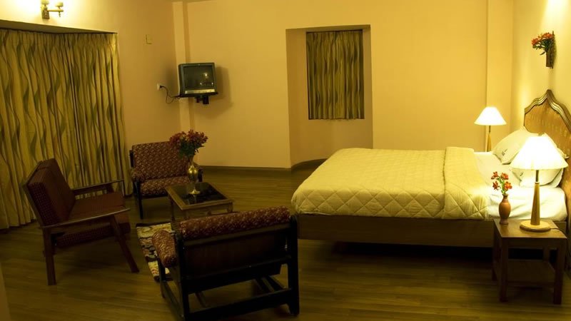 Spacious bedroom with double bed, seating area, television and warm lighting