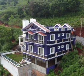 Luxury purple hillside hotel surrounded by greenery in Ooty