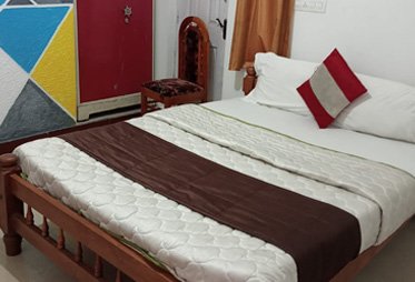 Traditional wooden bed in a vibrant Ooty guesthouse room