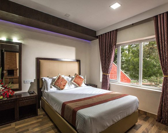 Elegant Ooty hotel room with large window and wooden flooring