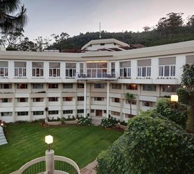Elegant resort with central lawn and scenic mountain backdrop in Ooty