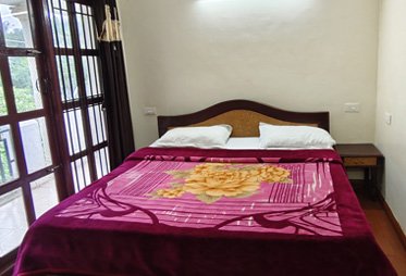 Bright bedroom with floral blanket and balcony view in Ooty homestay