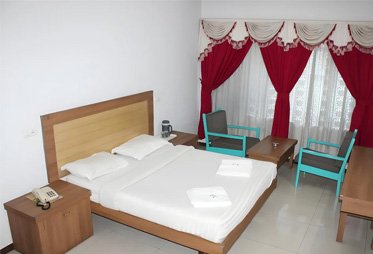 Spacious budget hotel room with wooden furniture and red curtain