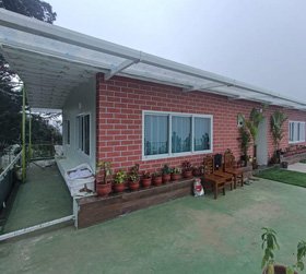 Brick wall homestay with outdoor seating and potted plants in Ooty
