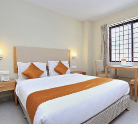 Comfortable double bedroom with orange accents in Ooty hotel