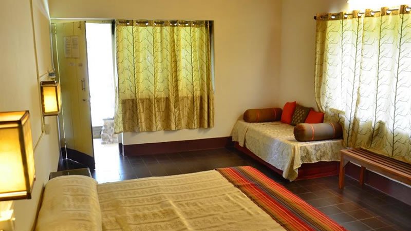 Spacious bedroom with beds, seating area, large windows and warm lighting