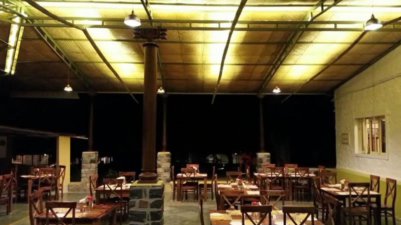 Open-air restaurant with wooden tables and chairs under a covered roof