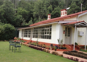 Charming white resort with a red roof, glass windows, and a lush green garden