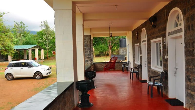 Spacious covered veranda with seating and hanging chair overlooking the outdoor grounds