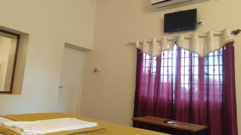 Simple bedroom with bed, television, air conditioning and curtained windows