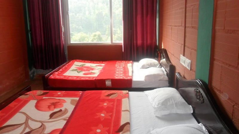 Twin bedroom with two beds, red walls and large window overlooking green hills