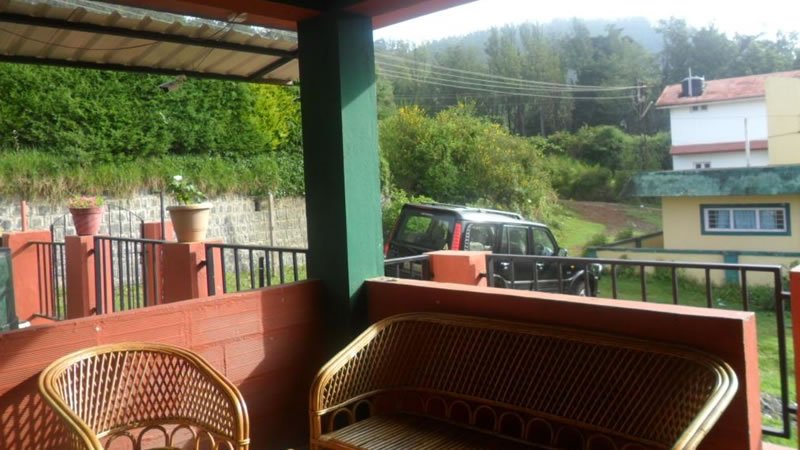 Veranda with wicker seating overlooking a garden, trees and surrounding greenery