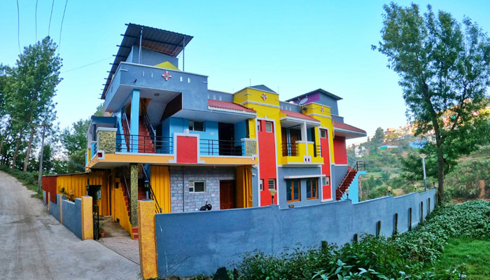 Colorful multi-story hillside cottage with blue, red, and yellow accents, balconies, and a modern design