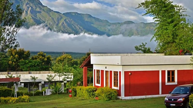 Red and white resort building with dramatic mountain and mist views