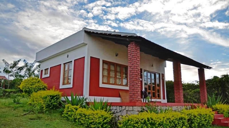 Red and white hillside holiday home with veranda and landscaped garden