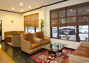 Cozy living hall with sofas, glass table, and bamboo blinds at Sunshine Cottage