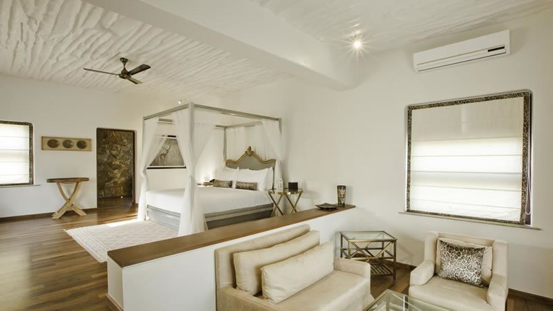 Spacious luxury suite with four poster bed, seating area and wooden flooring