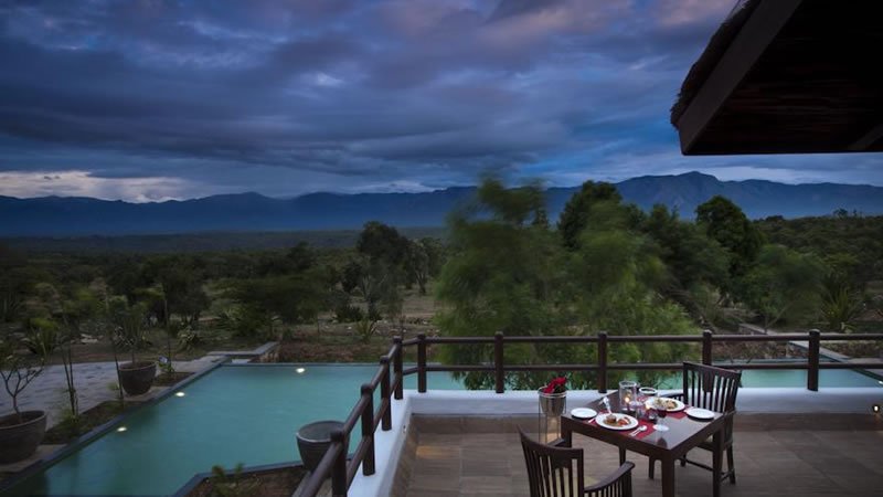 Outdoor poolside dining area overlooking trees and distant mountains