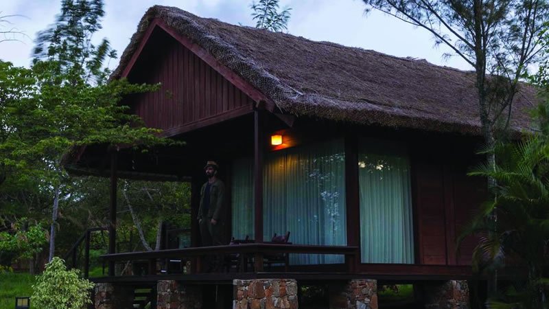 Rustic thatched roof cottage with private veranda surrounded by greenery
