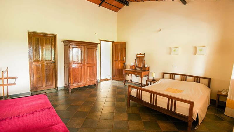 Spacious bedroom with wooden bed, wardrobe, dressing table and tiled flooring
