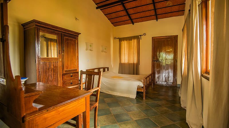 Bedroom with wooden bed, wardrobe, desk and large windows with natural light